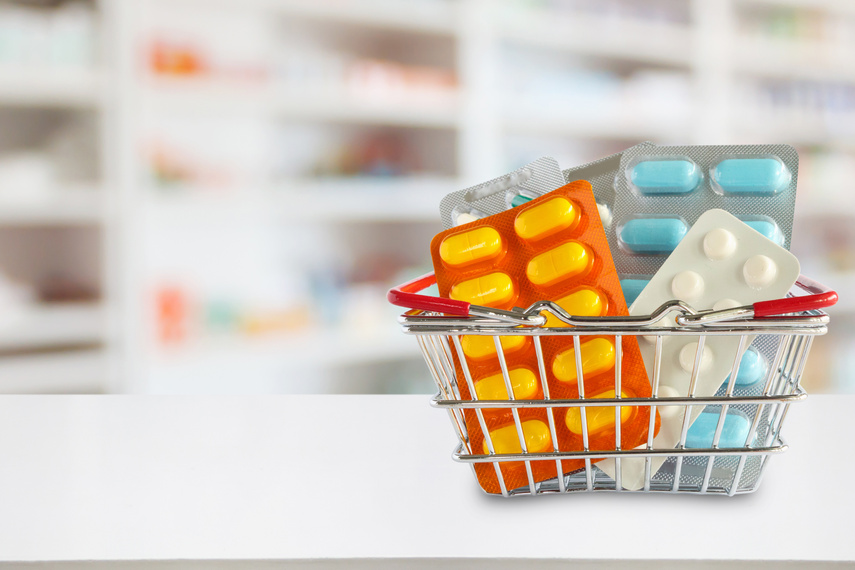 Medicine pills package in shopping basket with pharmacy drugstore shelves blur background